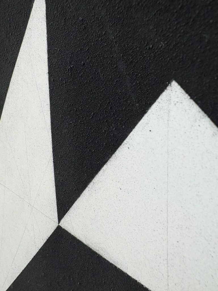 Detail of Black Rabbit of Inlé (Glyph Drawing No. 8), showing an even, sandy, tactile black charcoal texture, oil stick laid on by a brayer, interrupted by a sharp white shapes of the underlying paper with faint graphite grid lines.