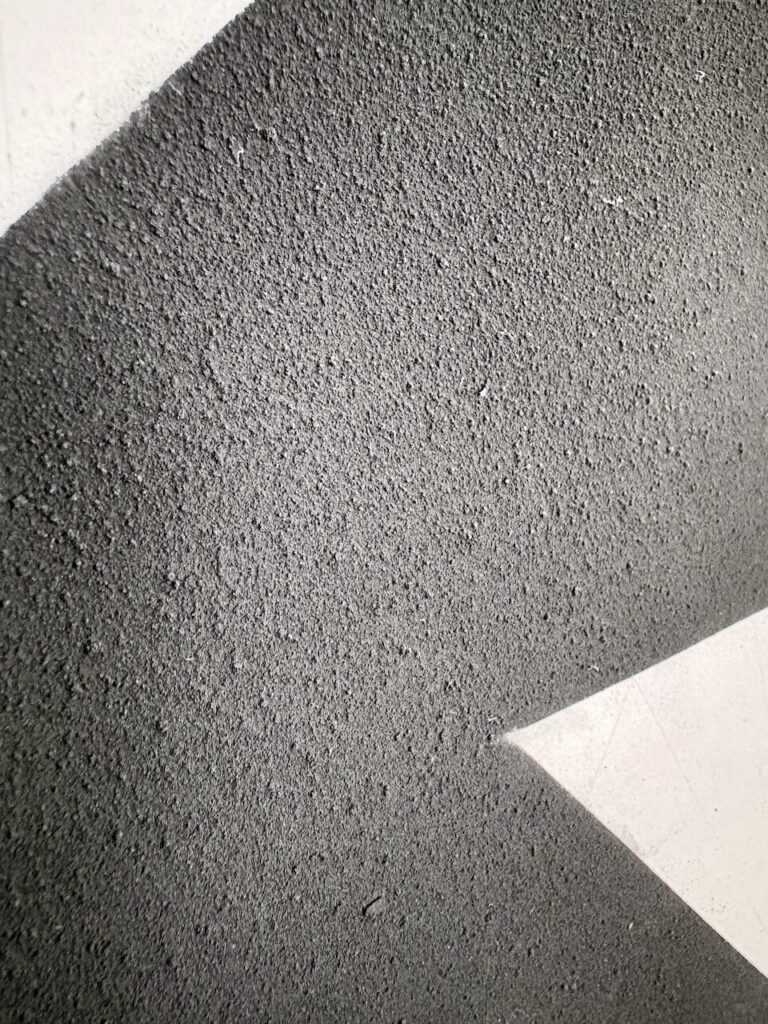 Detail of an Begging Dog (Glyph Drawing No. 4), showing an even, sandy, tactile texture, interrupted by a sharp white triangular shapes of the underlying paper with faint graphite grid lines.