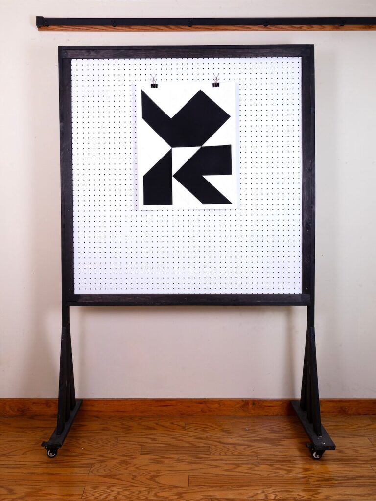 Begging Dog (Glyph Drawing No. 4) displayed on a studio pegboard partition, showing the full composition and providing scale context for the artwork.