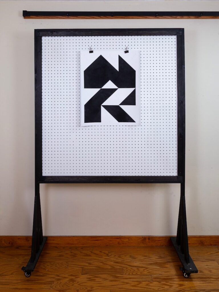 Mountain Lodge displayed on studio pegboard; textured abstract charcoal composition evoking mountains and forest iconography, showing scale and surface detail, inspired by rural Connecticut surroundings.