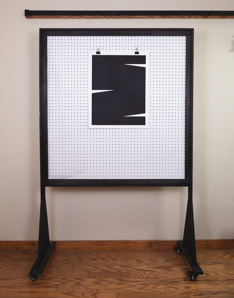 Minimalist wide shot of Untitled Drawing, No. 1 hanging on a white pegboard wall in the artist’s studio, with hardwood floors and a white wall in the background.