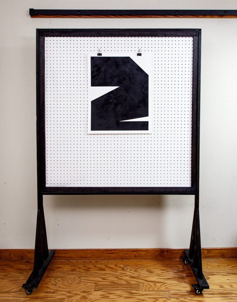 Minimalist wide shot of Untitled, Drawing No. 3 hanging on a white pegboard wall in the artist’s studio, with hardwood floors and a white wall in the background.