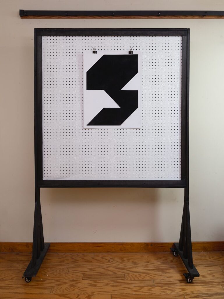 Wide shot of Unnamed Glyph (Glyph Drawing No. 4) hanging in the studio, showing the three-by-four grid composition and soft, textured charcoal surface.