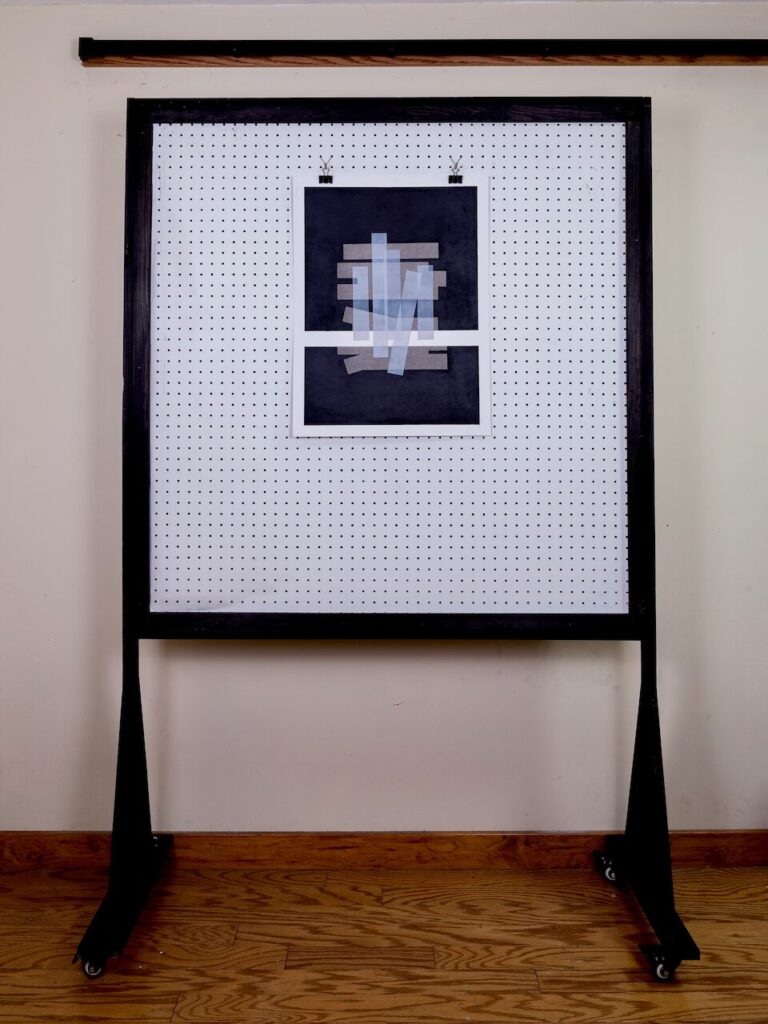 Spatial Bars, No. 1 in studio on pegboard wall, showing full 19 x 24" composition. Dark charcoal fields, middle-gray bars, and light-gray translucent acrylic bars visible; provides sense of scale.